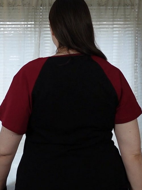 Frau in schwarzem T-Shirt mit roten Raglan-Ärmeln, Rückenansicht
